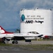 A United States Air Force Thunderbirds F-16 Fighting Falcon, numbered '4', is taxiing on the tarmac at Stewart Air National Guard Base. The aircraft displays the iconic red, white, and blue Thunderbirds livery. In the background, a large fuel storage tank bears the markings of the 105th Airlift Wing, New York Air National Guard (ANG).