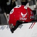 A red USAF flight helmet is resting on what appears to be the edge of a military aircraft cockpit. The helmet features the United States Air Force insignia, the text 'USAF', the number '3', and partial text reading 'Crim' (likely 'Crimson'). The aircraft surface below shows partial text reading 'SSgt Wy...dy', indicating a crew member's name.