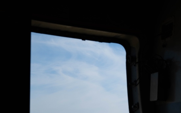 The image is taken from inside a large military aircraft, looking out through an open door or hatch onto a flight line. Visible on the tarmac are multiple aircraft with distinctive red, white, and blue livery consistent with the U.S. Air Force Thunderbirds aerial demonstration team. The aircraft are parked in a row on the apron with ground crew personnel visible nearby.