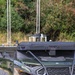 A Polaris utility vehicle (UTV) is equipped with a specialized payload system mounted on its rear cargo bed, featuring multiple vertical antennas and what appears to be a small drone or UAV on a launch/landing platform. The vehicle is olive/military green in color and bears the number '03' on its hood. The setup suggests a military, law enforcement, or research application involving unmanned aerial systems integrated with a ground vehicle.