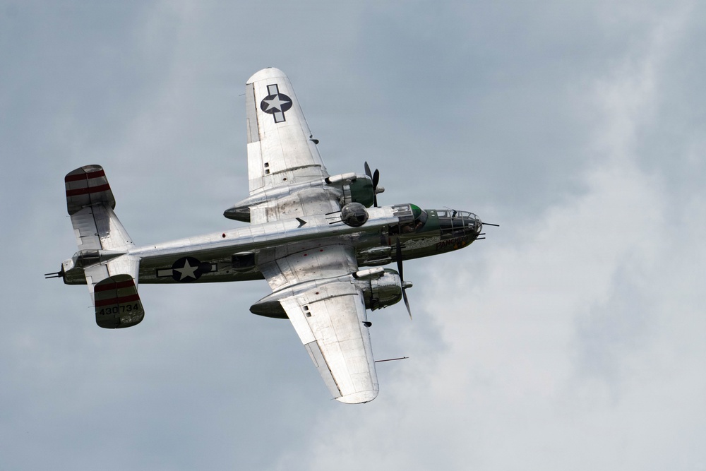 A vintage World War II-era American military bomber aircraft is photographed in flight from a low angle against an overcast sky. The aircraft displays USAAF markings including a white star insignia and the serial number 430734 on the tail. The plane appears to be a restored warbird, likely participating in an airshow or commemorative flight.