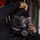 Forged Underwater: PNSY Dive Team Conducts Inspection of New Caisson A person in a black wetsuit is donning or adjusting a full-face diving mask with an integrated regulator. The mask visor shows water droplets, suggesting recent use or wet conditions. The scene appears to take place aboard a vessel, with another person visible in the background.