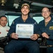 Three individuals pose for a photo aboard what appears to be a U.S. Navy vessel's bridge or command area. The central figure is holding a certificate titled 'Golden Eagle of the Day' dated 24 August 2026, presented to 'ET52 Cole J. Miller' from the USS Carl Vinson. The occasion appears to be a military recognition ceremony.