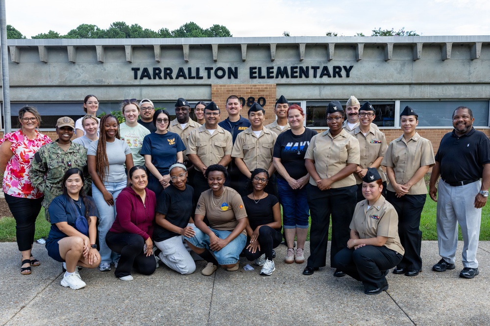 A group of approximately 25 people pose for a group photo in front of Tarrallton Elementary School. The group includes both uniformed U.S. Navy personnel in tan/khaki service uniforms and civilians in casual attire. This appears to be a community outreach or volunteer event connecting Navy service members with a local elementary school.