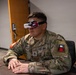 A U.S. Army soldier wearing camouflage OCP (Operational Camouflage Pattern) uniform is seated at a desk using FPV (First Person View) goggles, identifiable as 'Fat Shark' brand. The soldier's name tape reads 'MALTOS' and rank insignia indicates the grade of Sergeant (E-5). The setting appears to be an indoor military facility or office environment, suggesting a drone or simulation training exercise.