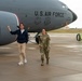 Two individuals stand on a military flight line in front of a U.S. Air Force aircraft, tail number 3542, bearing unit insignia and the marking '940 ARW' (Air Refueling Wing). One person is in civilian attire (blue hoodie, khaki pants, white sneakers) gesturing with a thumbs-up, while the other is in U.S. Air Force OCP (Operational Camouflage Pattern) uniform. The setting appears to be an active airfield tarmac, likely during a base visit or tour.