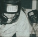 Two U.S. Marines wearing TITLE brand boxing headgear are photographed in what appears to be a training or sparring context. Both individuals are dressed in USMC digital camouflage uniforms. The image has a sepia/aged photographic tone with visible text identifying 'U.S. MARINES' and a partial surname 'CRUZ' on one uniform.