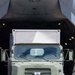 A military olive-drab truck is positioned at the open rear cargo ramp of a large military transport aircraft, appearing to be in the process of loading or unloading. The truck bears a military registration plate reading '96 49784' and displays a red number '2' marker on its front bumper. The scene is photographed from a direct front-facing perspective in bright daylight conditions.