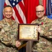 Two U.S. Army soldiers pose together holding a framed certificate from United States Army Japan titled 'The Order of the Bushido,' awarded to COL James C. Cheney. The soldier on the left, identified by his name tape as 'DOOGHAN,' appears to be a general officer based on his rank insignia, and is presenting the award. The recipient on the right is wearing a medal on his uniform, indicating this is a formal military awards ceremony.