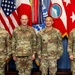Four military personnel in OCP (Operational Camouflage Pattern) uniforms pose for a formal group photograph in front of multiple flags. The individuals represent both U.S. Air Force and U.S. Army branches, identifiable by name tapes reading DAMIAN, JOST, DOOCHAN, and LANGLEY. The setting appears to be an official military headquarters or command facility.