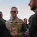A U.S. Air Force officer identified by name tape as 'WILSBACH' with four-star rank insignia is engaged in conversation with other military personnel. The central figure wears OCP (Operational Camouflage Pattern) uniform with 'U.S. AIR FORCE' tape and sunglasses. At least one individual in the background wears a uniform with what appears to be a Polish flag patch, suggesting a multinational military engagement.
