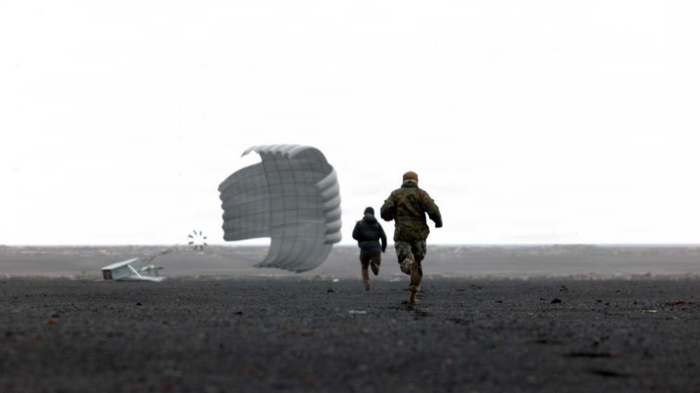 Two individuals are running across a dark, flat terrain toward a deployed parachute and what appears to be a landed cargo or equipment container. One person is wearing military camouflage uniform while the other is in darker civilian-style clothing. The scene appears to be a military airdrop recovery operation conducted under overcast sky conditions.
