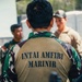 The image shows military personnel in a group setting, with the foreground figure wearing a distinctive Indonesian Marine Corps uniform. The back of the vest reads 'INTAI AMFIBI MARINIR', identifying the wearer as a member of the Indonesian Marine Amphibious Reconnaissance unit. At least one Western military personnel in tan/MultiCam uniform is visible in the background, suggesting a joint or multinational military exercise.