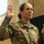 Lt. Col. Hughes and Lt. Col. Pitts promotion ceremony to colonel A U.S. Army Colonel is raising her right hand, appearing to take an oath or be sworn in during a military ceremony. Her uniform displays the name tape 'HUGHES' (partially visible) and an eagle insignia indicating the rank of Colonel (O-6). A second uniformed soldier is partially visible to the right.