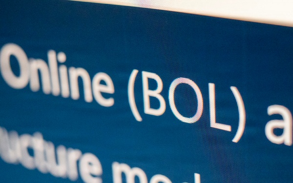 The image shows a close-up photograph of a digital screen displaying white text on a dark blue background. The visible text references 'Online (BOL) and' on the first line, followed by 'Infrastructure modernization' on subsequent lines. The text appears to be part of a presentation slide or webpage, partially cropped at the edges.