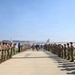 A formal military honor cordon ceremony is taking place on an airfield tarmac, with two long rows of soldiers in camouflage uniforms and red berets lining a walkway. A small group of individuals, including civilians and military personnel, walk between the rows while soldiers applaud. An American Airlines aircraft is visible in the background, suggesting this is a commercial or joint-use airport.