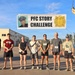 A group of eight participants pose in front of a banner reading 'PFC Story Challenge' at what appears to be a military installation. The banner features a portrait photo of a uniformed soldier and a military unit insignia with the number 9. Participants are wearing race bibs with visible numbers including 52, 76, 49, 31, 19, and 80.