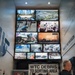 The image shows visitors viewing a museum exhibit related to the September 11, 2001 attacks, featuring a large multi-screen video wall displaying archival footage and photographs of Ground Zero, the Pentagon, and New York City. A prominent 'WTC Debris to Sorting Area' sign is displayed alongside a damaged NYPD vehicle. The exhibit appears to be part of the 9/11 Memorial Museum or a related USACE (U.S. Army Corps of Engineers) traveling exhibition titled 'USACE at the Pentagon: Building for Resilience.'