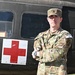 A U.S. Army Sergeant in Operational Camouflage Pattern (OCP) uniform stands with arms crossed in front of a military medical vehicle marked with a Red Cross symbol. The soldier wears a name tape reading 'WHEELER' and an 'ARMY' tape, along with a 'COMPETITOR 6' armband on the right sleeve. The image appears to be an official or semi-official portrait-style photograph.