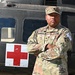 A U.S. Army soldier named Salsberry stands with arms crossed in front of a military medical helicopter marked with a red cross symbol. The soldier is wearing OCP (Operational Camouflage Pattern) uniform with visible name tape, U.S. Army tape, and a unit patch on the left sleeve. A 'Competitor 17' tab is visible on the right sleeve, suggesting this may be a competition or best warrior event photo.