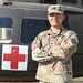 A U.S. Army soldier in Operational Camouflage Pattern (OCP) uniform stands with arms crossed in front of a military medical helicopter marked with a Red Cross symbol. The soldier's name tape reads 'PADILLA' and the right chest tape reads 'US ARMY'. A 'COMPETITOR 10' tab is visible on the left shoulder, and a unit patch is on the left sleeve.