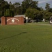 The image shows the entrance sign for 'Sound of Freedom GC' (Golf Course) at MCAS Cherry Point, a Marine Corps Air Station. Multiple golf carts and players are gathered in what appears to be a tournament or group outing staging area. The scene is set on a well-maintained golf course with lush green fairways and mature trees in the background.