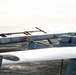 The image shows one or more unmanned aerial vehicles (UAVs/drones) positioned on what appears to be the deck of a naval vessel at sea. The UAVs have a fixed-wing design with a pusher propeller configuration and appear to be military or surveillance-grade systems. The ocean is visible in the background, confirming a maritime operational environment.