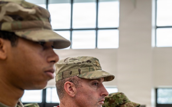 The image shows a formation of military personnel standing at attention inside a large building with tall windows. Two U.S. Army soldiers in OCP (Operational Camouflage Pattern) uniforms are prominently visible in the foreground, with name tapes reading 'RODRIGUE[Z]' and 'PHILIPPS'. Behind them, a row of soldiers wearing a different camouflage pattern — consistent with Japanese Ground Self-Defense Force uniforms — suggests this is a joint military exercise or ceremony.