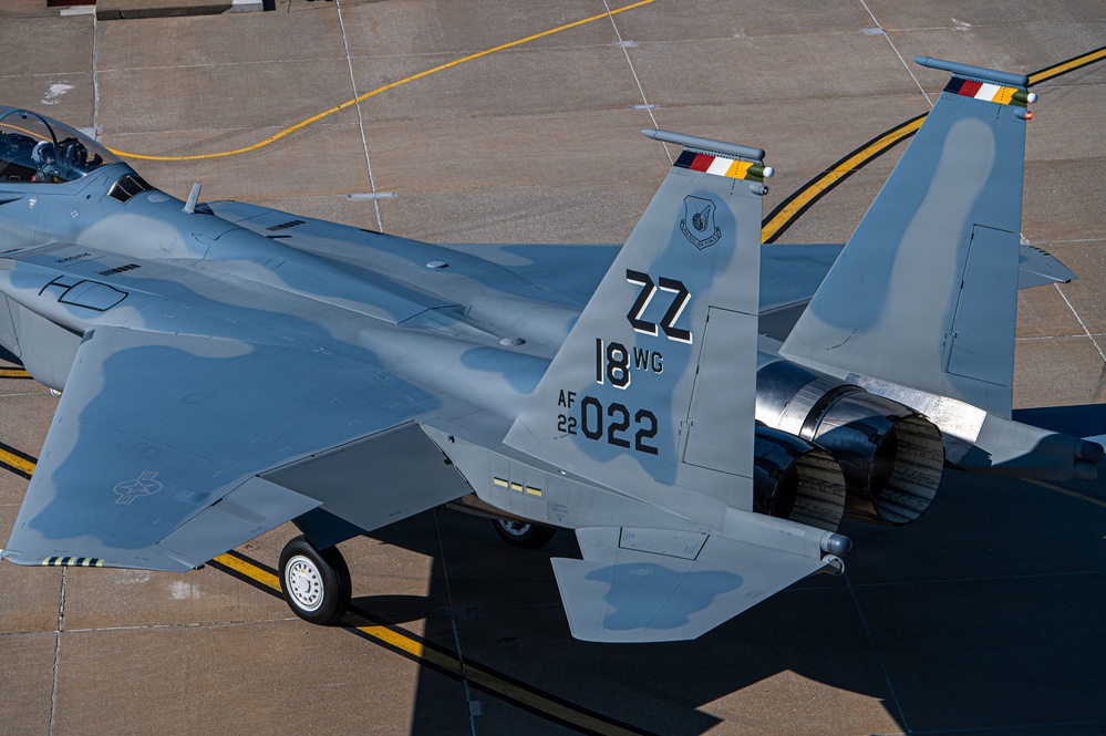 An aerial view of a U.S. Air Force F-15 Eagle fighter jet parked on a concrete flight line apron. The aircraft bears tail code 'ZZ' indicating assignment to the 18th Wing at Kadena Air Base, Japan, with serial number AF 22-022. The image is taken from an elevated angle, likely from a tower or elevated structure, showing the aircraft's upper fuselage, twin tail fins, and dual engine exhausts.