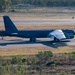 A U.S. Air Force B-52 Stratofortress strategic bomber is taxiing on a runway at what appears to be an airfield in a tropical or semi-arid environment. The aircraft bears the 'LA' tail code, indicating assignment to Barksdale Air Force Base, Louisiana, home of the 2nd Bomb Wing. The setting, with dry grass and eucalyptus-type vegetation, suggests this may be RAAF Base Darwin or a similar Australian airfield.