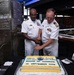 Two U.S. Navy Captains in white dress uniforms are cutting a ceremonial cake with a sword at a Change of Command ceremony. The cake identifies the incoming commander as CAPT Hines and the outgoing commander as CAPT Fontaine, dated 03 September 2026. The event appears to be held in a military club or dining facility.