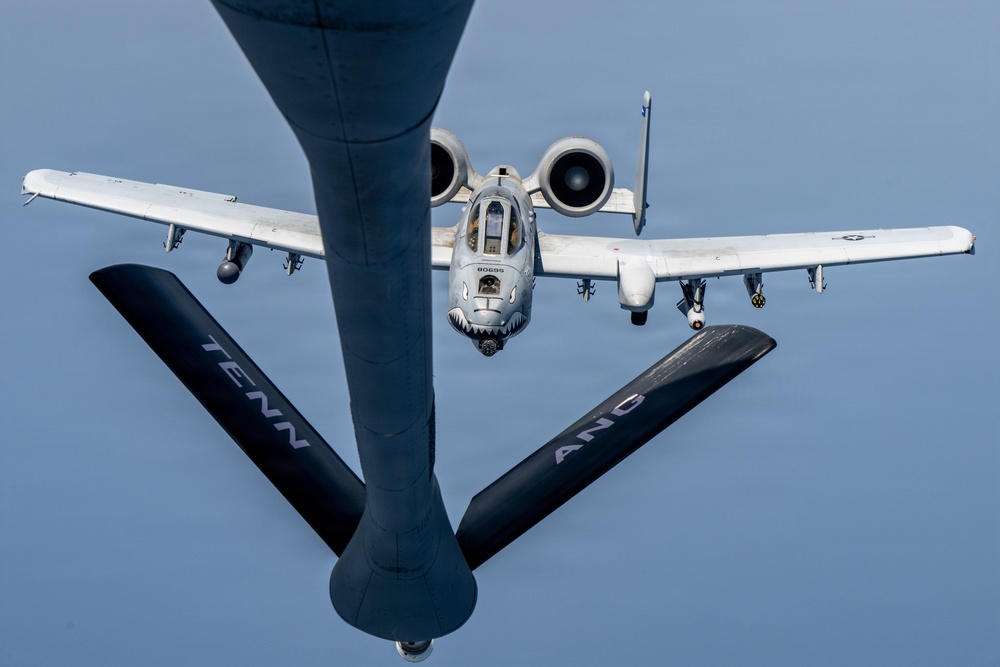An A-10 Thunderbolt II (Warthog) attack aircraft is approaching a tanker aircraft for aerial refueling, photographed from the boom operator's position on the tanker. The receiving aircraft bears a shark mouth nose art and the serial number 80695. The tanker's refueling boom is visible in the foreground, marked with 'TENN ANG' indicating Tennessee Air National Guard.