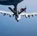 An A-10 Thunderbolt II (Warthog) attack aircraft is conducting aerial refueling, connected to a tanker aircraft's refueling boom visible at the top of the frame. The A-10 features a distinctive shark mouth nose art and markings indicating it belongs to a Tennessee Air National Guard unit. The photograph is taken from the tanker aircraft looking down at the receiver aircraft against a clear blue sky.
