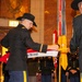 A formal U.S. Army military ceremony is taking place in an ornate indoor venue, likely a state capitol or government building. Two soldiers wearing distinctive black cavalry Stetsons are handling a unit guidon or flag bearing the text '152ND CAVALRY.' Additional soldiers in dress uniforms stand in formation holding flags and streamers in the background.