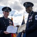 Two U.S. military personnel in dress uniforms are jointly holding an official certificate during what appears to be a formal awards ceremony held outdoors. The document is visibly titled 'Defense Superior Service Medal' issued by the United States of America. Both individuals are smiling, suggesting a celebratory and ceremonial occasion.