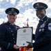 Two United States Space Force personnel in dress uniforms are posing together while holding a Certificate of Retirement. The certificate is issued to Jacob C. Simmons, retired from the United States Space Force on the first day of February 2027. The ceremony appears to be taking place outdoors with military flags visible in the background.