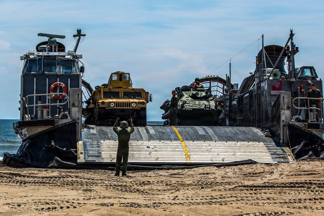 A Marine with the Landing Force Shore Party, or LFSP, navigates the Combat Anti-Armor Team, or CAAT, with the 24th Marine Expeditionary Unit’s Ground Combat Element, Battalion Landing Team 3rd Battalion, 6th Marine Regiment, off a Landing Craft Air Cushion, or LCAC, from the USS Iwo Jima’s Assault Craft Unit 4, during a tactical offload of 24th MEU personnel and equipment at Onslow Beach, N.C., August 12, 2014. The offload was part of Amphibious Squadron/Marine Expeditionary Unit Integration, the second major exercise for the 24th MEU. The USS Iwo Jima is part of the Iwo Jima Amphibious Ready Group. (U.S. Marine Corps photo by Cpl. Mary M. Carmona)
