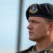 A close-up portrait of a male military service member wearing a black beret with a 'Defensor Fortis' insignia badge, indicating affiliation with the United States Air Force Security Forces. He is dressed in a multicam/OCP camouflage uniform and appears to be at attention or standing in a formal posture. The image is a sharp, professional-quality photograph with a blurred background.