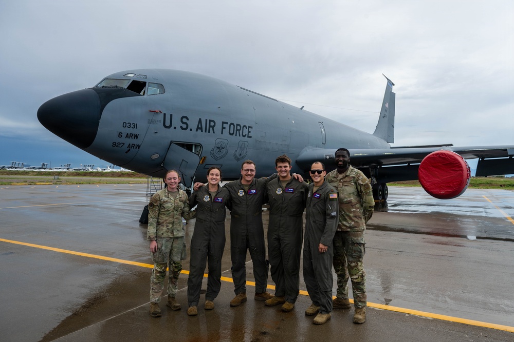 Six U.S. Air Force personnel pose together on a wet tarmac in front of a KC-135 Stratotanker aircraft marked with tail number 0331, assigned to the 6th Air Refueling Wing (6 ARW) and 927th Air Refueling Wing (927 ARW). The group consists of a mix of flight crew members in olive/sage green flight suits and support personnel in OCP (Operational Camouflage Pattern) uniforms. The overcast, rainy conditions suggest a post-mission or deployment photo opportunity.