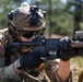 A U.S. Army soldier identified as 'Zahler' is in a prone firing position aiming a rifle with an attached optic and accessories. The soldier is wearing full tactical gear including a FAST-style helmet with night vision device mount, multicam uniform, tactical gloves, and a wristwatch. The setting appears to be an outdoor training range or field exercise environment.