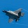 The F-35A Lightning II offically arrives at the 104th Fighter Wing, brings new era to Barnes Air National Guard Base A single-engine stealth fighter jet, identifiable as an F-35 Lightning II, is captured in flight against a clear blue sky. The aircraft is shown in a banked maneuver, revealing its top surface, with visible wingtip vortex condensation trails streaming from the wings. The gray paint scheme and distinctive delta-wing design are clearly visible.