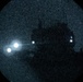 An all-sky or fisheye lens photograph of the night sky, captured in a circular frame against a black background. The image shows several bright point sources of light distributed across the field, with a dark silhouette of what appears to be a structure or tree visible in the upper-right quadrant. The image has significant grain/noise, consistent with a long-exposure or low-light night sky camera.