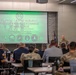A military and law enforcement conference is taking place in a modern conference room. The presentation screen displays 'El Paso LASING Subject Matter Expert Exchange Conference' organized by Counterintelligence Coordinating Authority, Joint Task Force – Southern Border, and Army Criminal Investigation Division. An officer in military camouflage uniform is speaking at a podium to an audience of mixed military and civilian attendees.