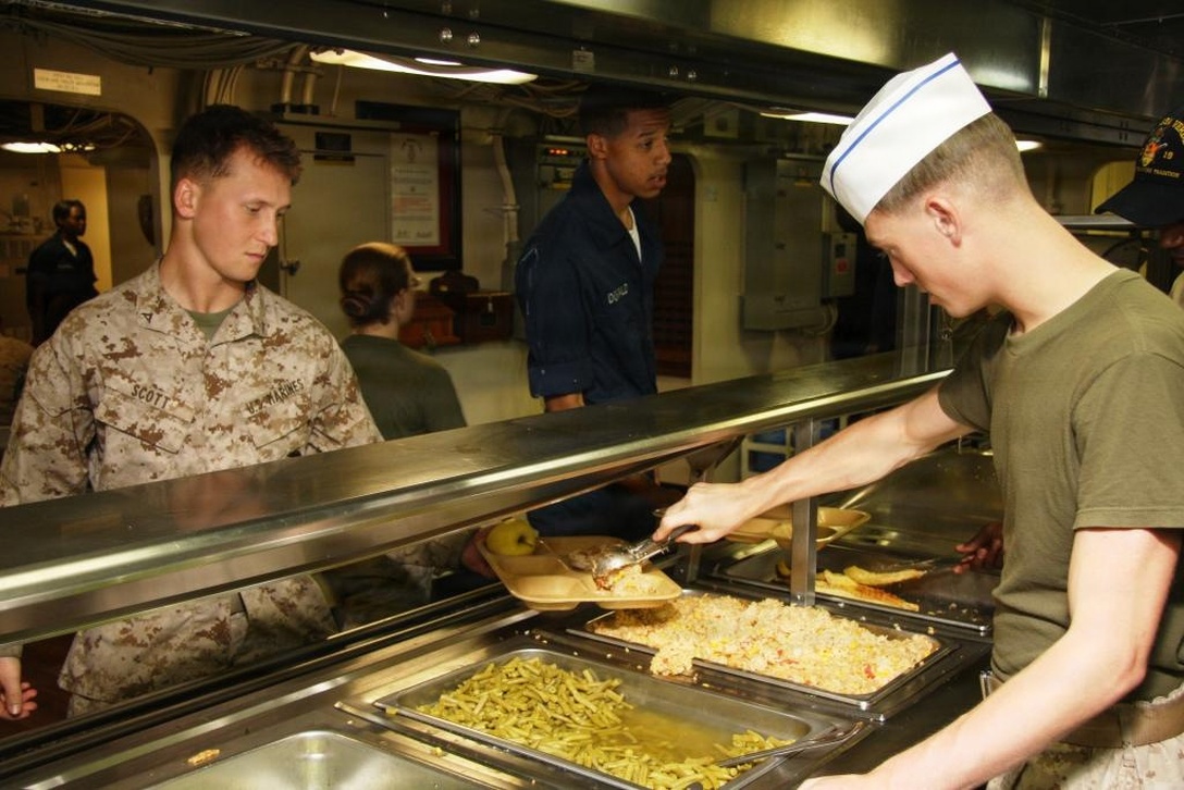 As the lines seem to never shorten, the Marines and Sailors behind the counters continue their duties as messmen, serving up hot food to any Marine or Sailor who may pass through their line. There is a variety of meal selections that the Marines and Sailors have to choose from and it is the job of the messmen to provide them nutritious meals on their trays.