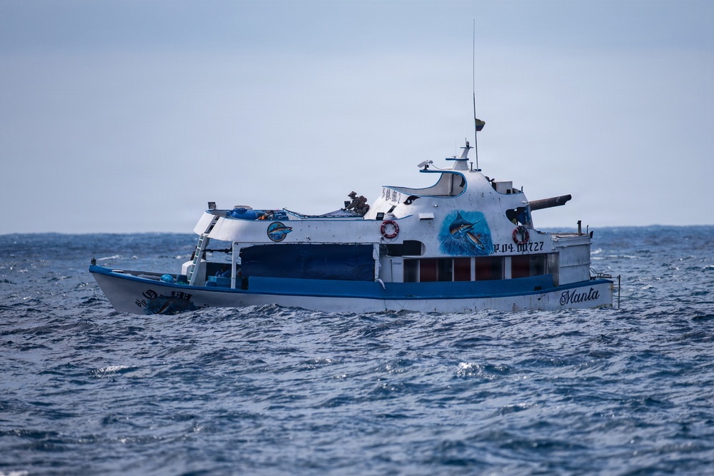 A white and blue fishing/charter boat named 'Manta' with registration number P.04 00727 is navigating choppy open ocean waters. The vessel features decorative artwork of a marlin/swordfish on its hull and appears to be a mid-sized sport fishing or dive charter boat. The sea conditions appear moderately rough with visible wave action.