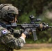 A South Korean special operations soldier is shown in a firing stance, aiming a rifle in an outdoor environment. The soldier is equipped with advanced tactical gear including a helmet with 'Special Recon' markings, communication headset, and a modern assault rifle with optics. The South Korean flag patch is clearly visible on the left shoulder of the camouflage uniform.