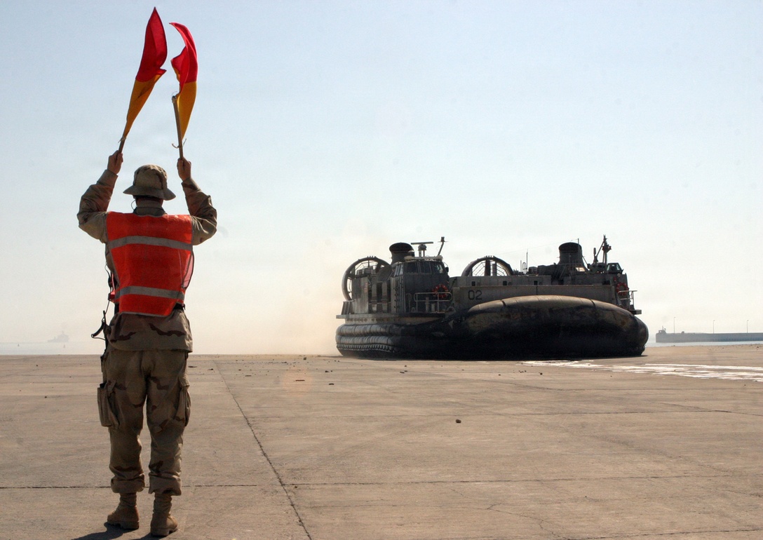 A Landing Craft Air Cushioned is guided to the shore by a Sailor serving with the 24th Marine Expeditionary Unit (Special Operations Capable) during the MEU?s offload into Kuwait on Oct. 4.  The LCACs are instrumental in ensuring the Marines? gear and personnel are brought ashore quickly and safely.