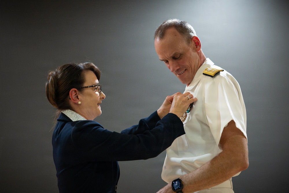 Ms Elizabeth Nashhold Pins the Legion of Merit star onto Rear Admiral Scott Brown