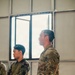 Two military personnel are standing indoors, appearing to attend a briefing or training session. The foreground figure wears US Army MultiCam (OCP) uniform with multiple qualification tabs, while the background figure wears a Philippine Armed Forces woodland camouflage uniform with a 'TERP' (interpreter) patch. This appears to be a joint US-Philippine military exercise or training event.