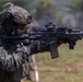 A Republic of Korea (ROK) Army soldier is shown in a combat-ready stance, aiming a rifle with optical sights attached. The soldier is wearing full tactical gear including a camouflage uniform, tactical helmet with accessories, ear protection, and a face mask. The setting appears to be an outdoor training or exercise environment.